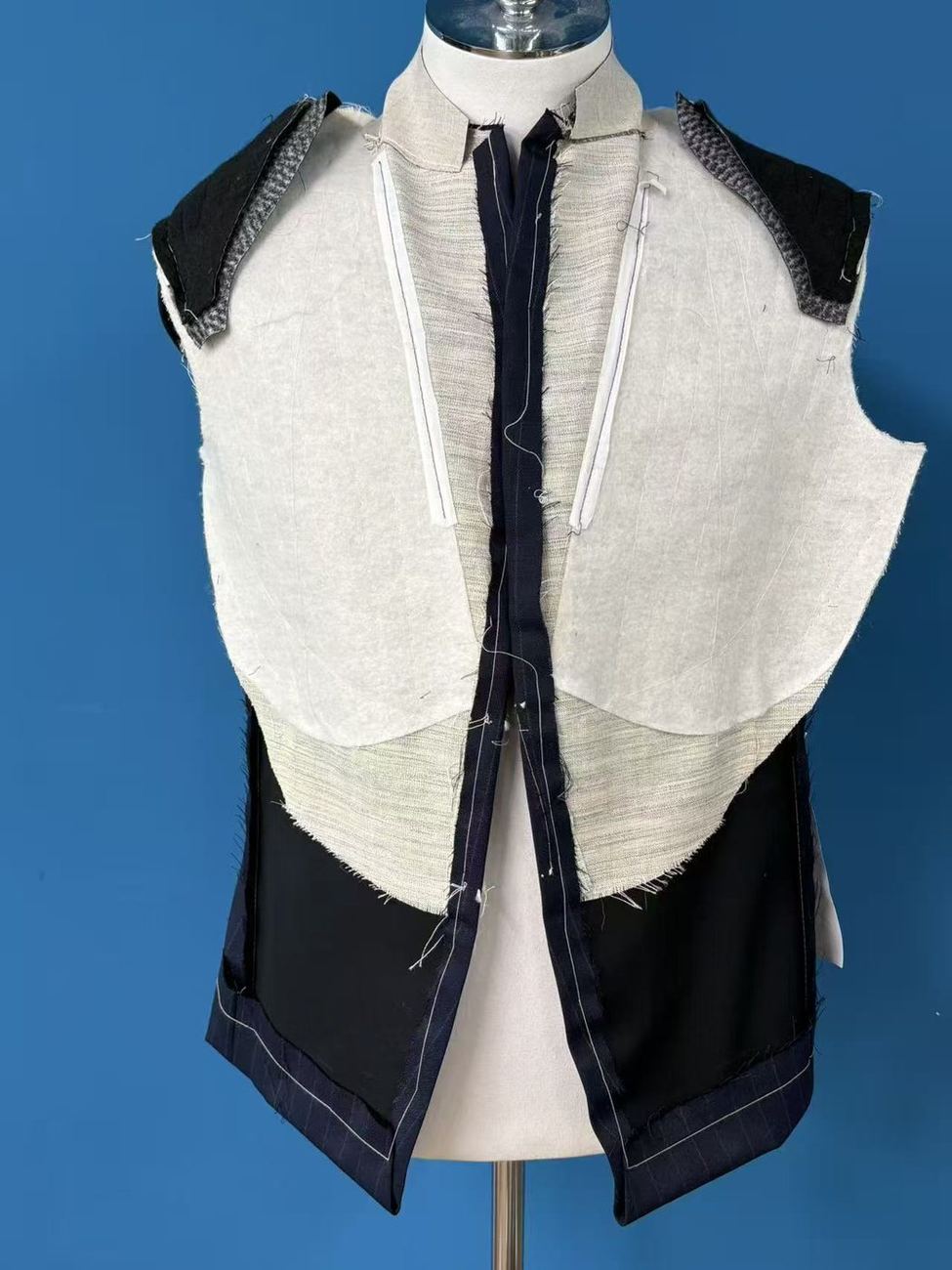 A jacket front opened on a dress form to show a half canvas: the canvas layer runs through the chest and lapel and stops above the waist.